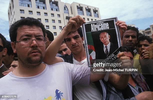 Jeunes gens montrant un portrait de Mohamed Boudiaf lors des obsèques du chef de l'Etat assassinè le 1er juillet 1992 à Alger, Algérie.