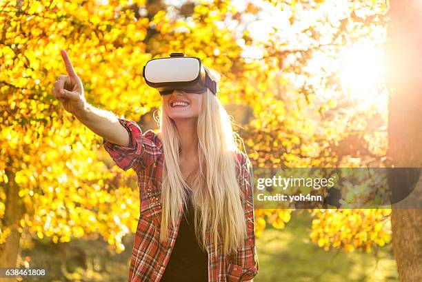 blonde frau spielt im freien mit vr-headset - head mounted display stock-fotos und bilder