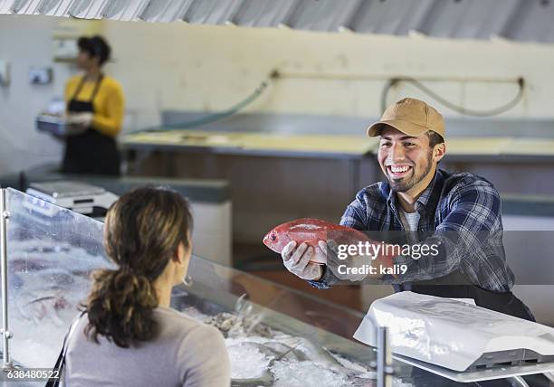 lavoratore nel mercato dei frutti di mare che aiuta il cliente - pescivendolo foto e immagini stock