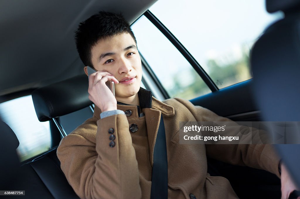 Junge asiatische Mann halten Handy im Auto