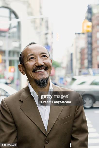 asian mature man looking upward in downtown city - tibetan culture stock pictures, royalty-free photos & images