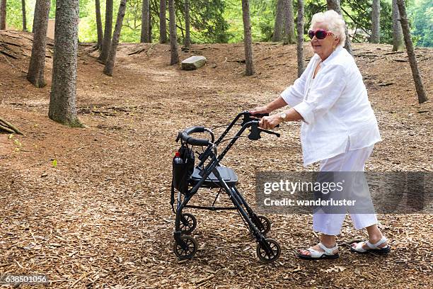 pousser le promeneur à travers une forêt - déambulateur rollator photos et images de collection