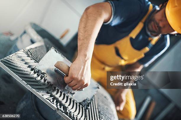 tile handyman applying adhesive on a tile. - troffel stockfoto's en -beelden