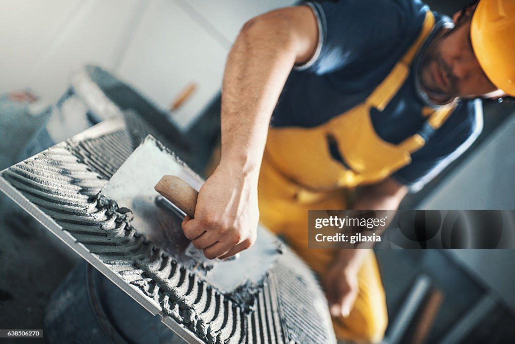 Tile handyman applying adhesive on a tile.