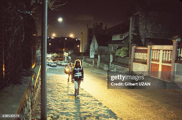 Femme marchant dans la rue de nuit dans les années 1980 à Paris, France.