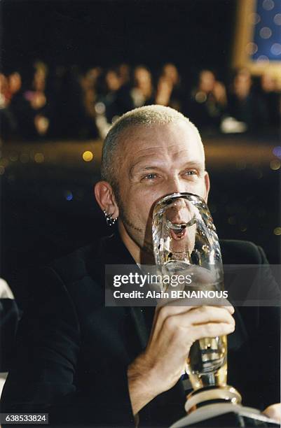 Le couturier Jean-Paul Gaultier fête sa récompense en buvant dans son trophée, le 21 novembre 1996, à Paris, France.