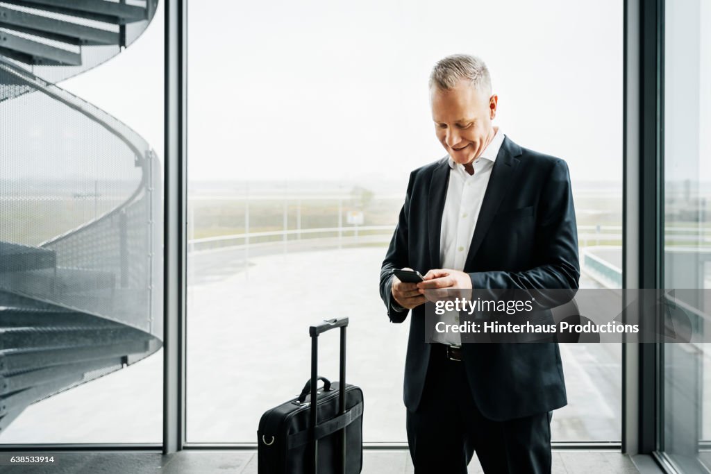 Businessman with smart phone standing at airport