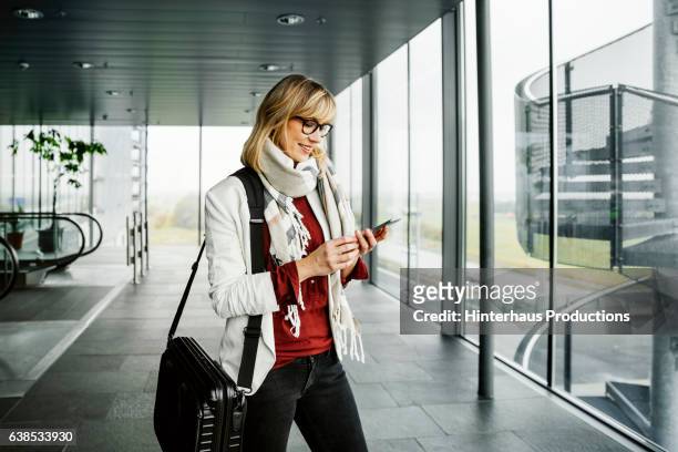 businesswoman with smart phone standing at the airport - airport stairs stock pictures, royalty-free photos & images
