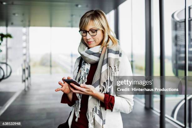 businesswoman with smart phone standing at the airport - white collar worker fotografías e imágenes de stock