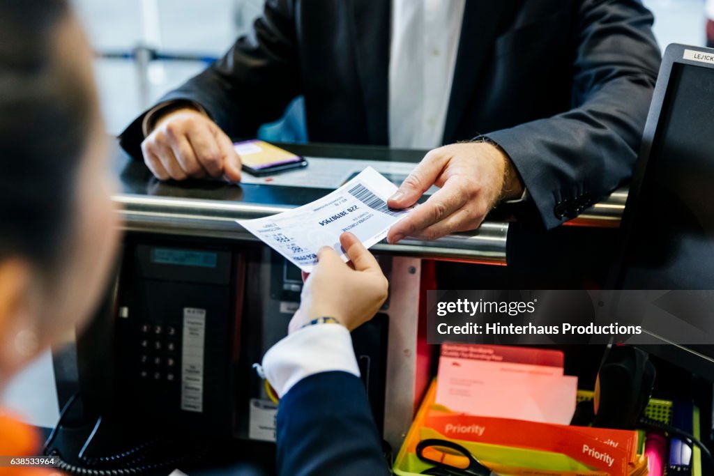 Businessman getting his boarding pass at check-in counter