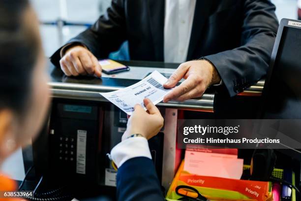 businessman getting his boarding pass at check-in counter - aeroplane ticket stock pictures, royalty-free photos & images
