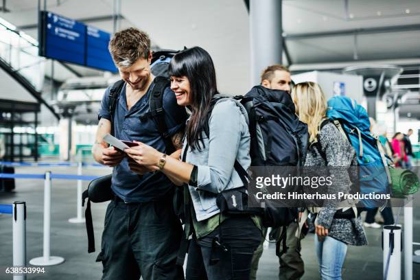 backpackers with smart phone waiting at airline checkin counter - tourist stock-fotos und bilder