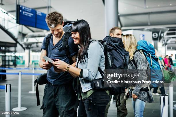 backpackers with smart phone waiting at airline checkin counter - couple smartphone happy stock pictures, royalty-free photos & images