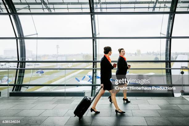 two flight attendants on the way to their plane - tripulación fotografías e imágenes de stock