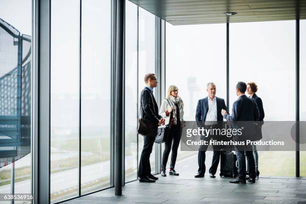 group of mature business travellers meeting at the airport and talking - fünf personen stock-fotos und bilder
