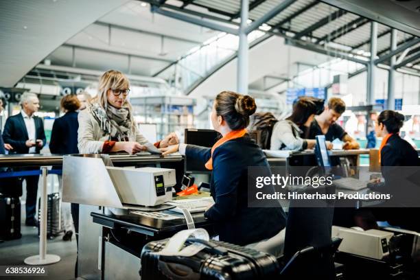 travellers at an airport checkin counter dropping their luggage and getting boarding passes - 搭乗手続き ストックフォトと画像