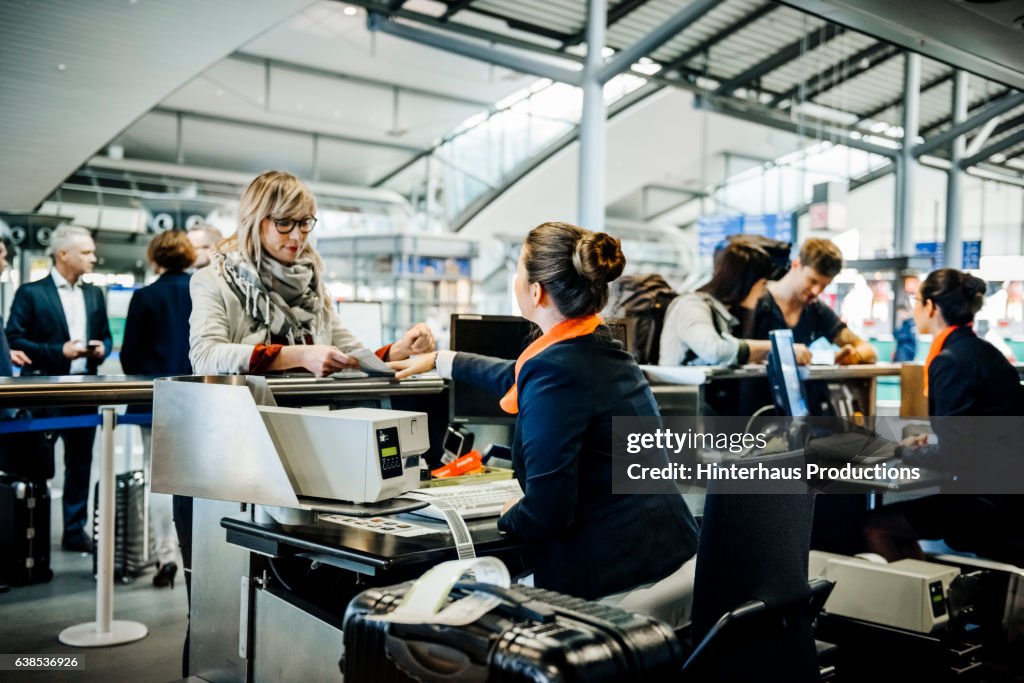 Travellers at an airport checkin counter dropping their luggage and getting boarding passes
