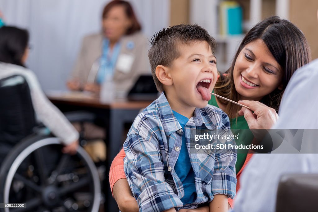 Doctor checks young patient's throat during exam