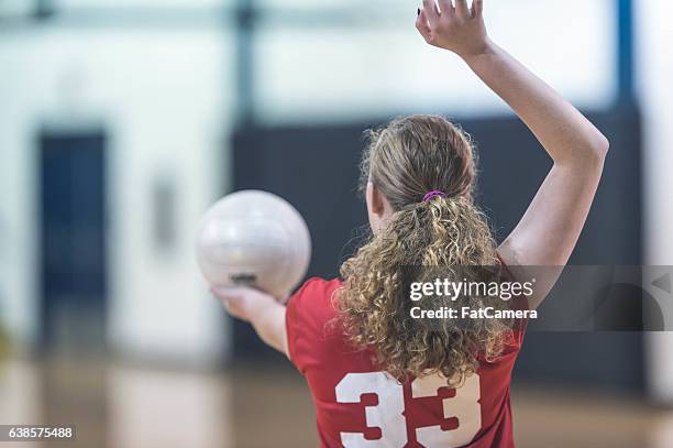 jugadora de voleibol femenina de la escuela secundaria sirviendo durante un partido - pelota de vóleibol fotografías e imágenes de stock