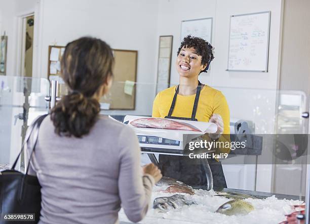 woman in seafood market helping customer - fishmonger stock pictures, royalty-free photos & images
