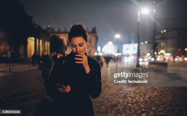 jovem andando em berlim à noite checando telefone - vinho quente - fotografias e filmes do acervo