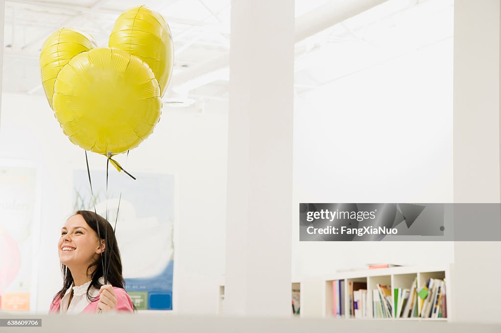 Mujer sosteniendo globos de helio en el cargo