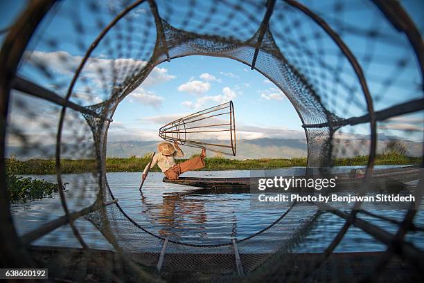 fisherman with traditional fishing net in inle lake, myanmar - heritage round one stock-fotos und bilder