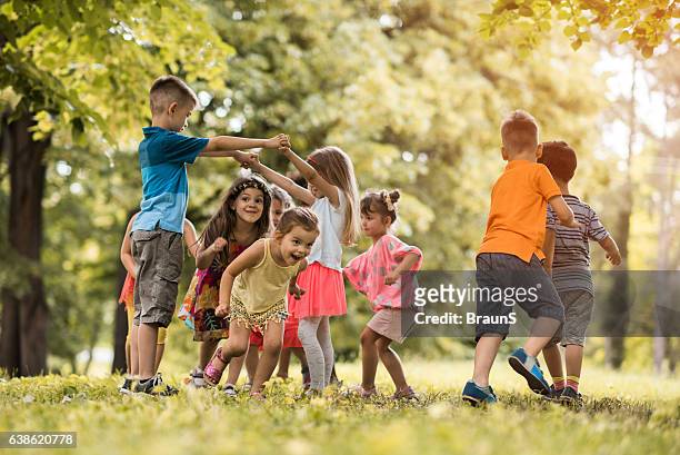 group of small kids having fun while playing in nature. - kindertijd stockfoto's en -beelden