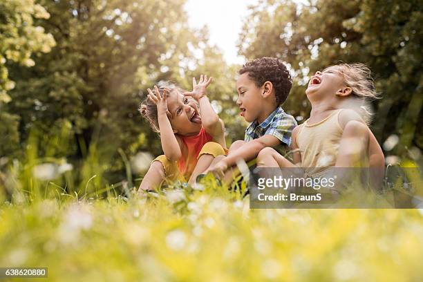 amigos pequenos se divertindo enquanto relaxam na grama. - somente crianças - fotografias e filmes do acervo