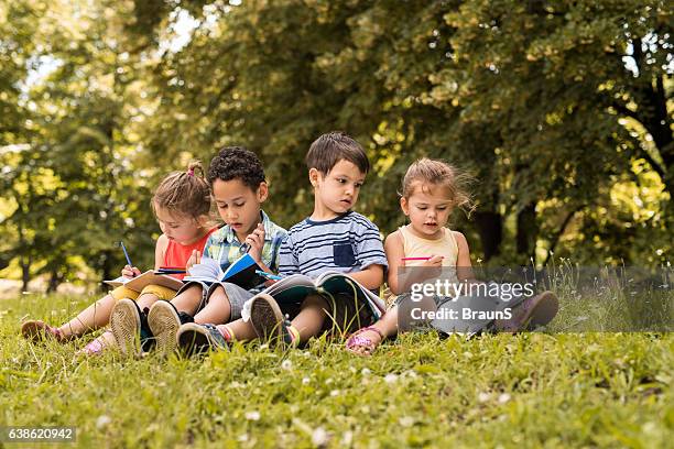 group of cute kids writing in notebooks at the park. - report fun stock pictures, royalty-free photos & images