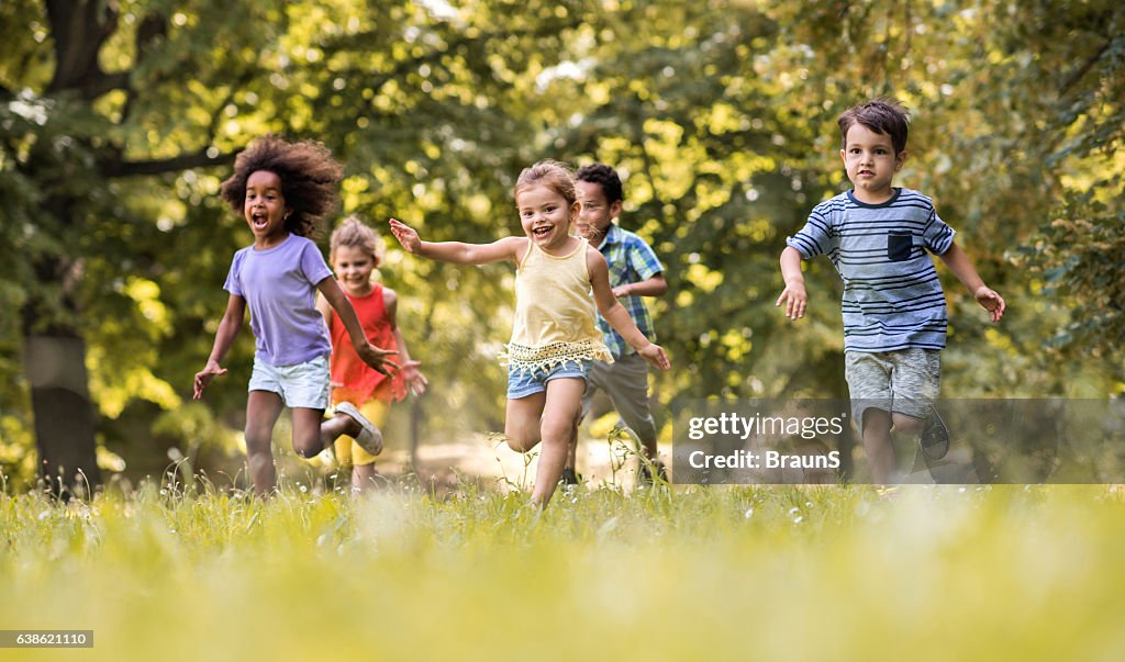 Grupo de niños felices divirtiéndose mientras corriendo en la naturaleza.