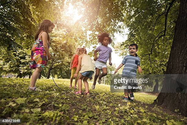 group of playful kids having fun while skipping jump rope. - springtouw stockfoto's en -beelden