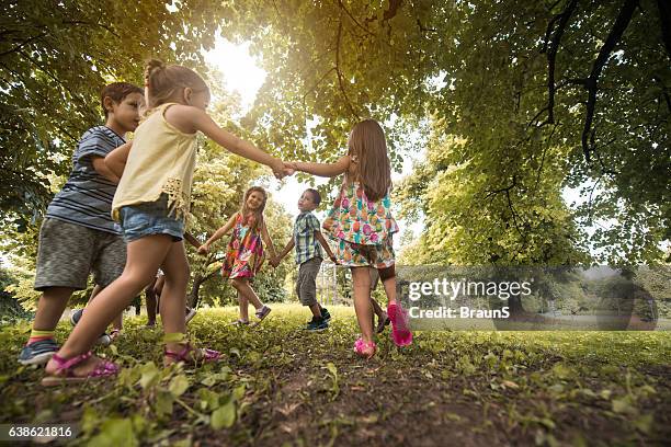 below view of small friends playing ring-around-the-rosy in the park. - ring around the rosy stock pictures, royalty-free photos & images