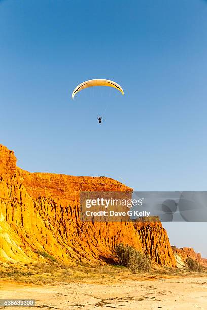 paragliding by red cliffs - hängegleiter stock-fotos und bilder