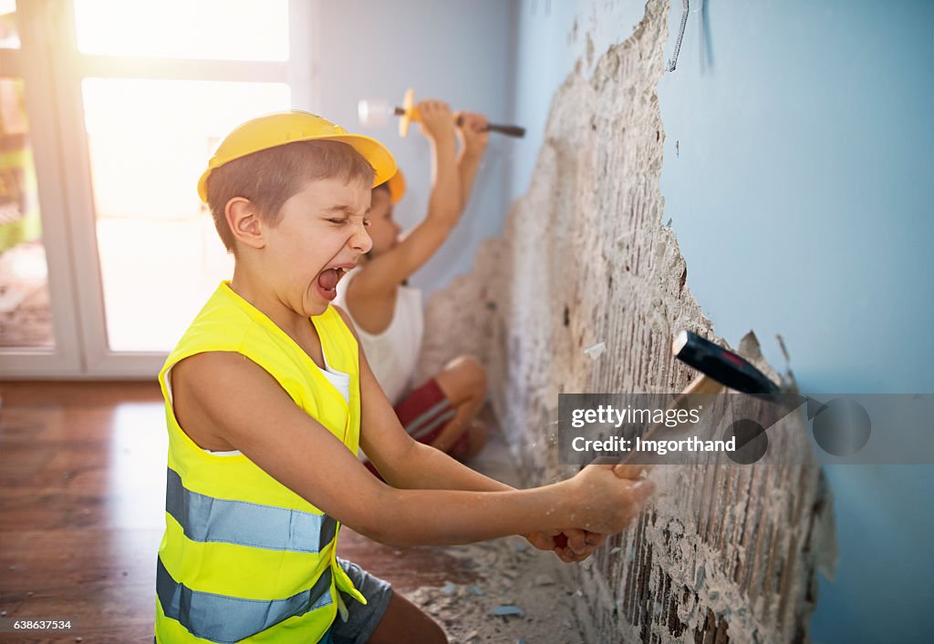 Dos pequeños trabajadores arrancando yeso en su habitación