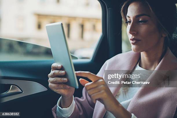 woman with digital tablet in a car - high society stock pictures, royalty-free photos & images