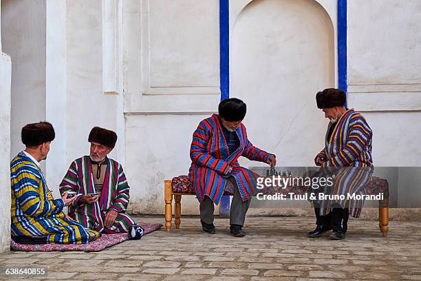 uzbekistan, bukhara, men in chapan playing chess - uzbekistan stock-fotos und bilder