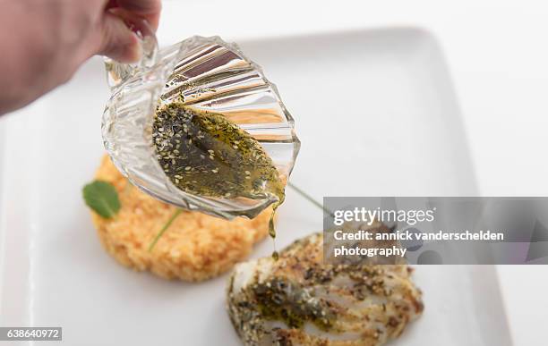 pouring za'atar-wu-zayt sauce on codfish dish. - origanum stock pictures, royalty-free photos & images
