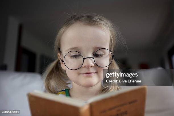 child (3-4) wearing specatcles and reading book - intellectual ventures stock pictures, royalty-free photos & images