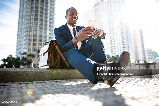 businessman texting in miami sitting on the park - miami business imagens e fotografias de stock