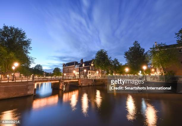 canal bridges illuminated at dusk with reflection on canal waters, amsterdam - canal disney stock pictures, royalty-free photos & images