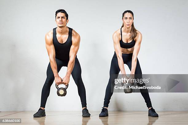 beautiful hispanic couple lifting kettlebells together - couple in a train stock pictures, royalty-free photos & images