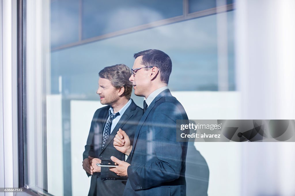 Business men standing together behind glass