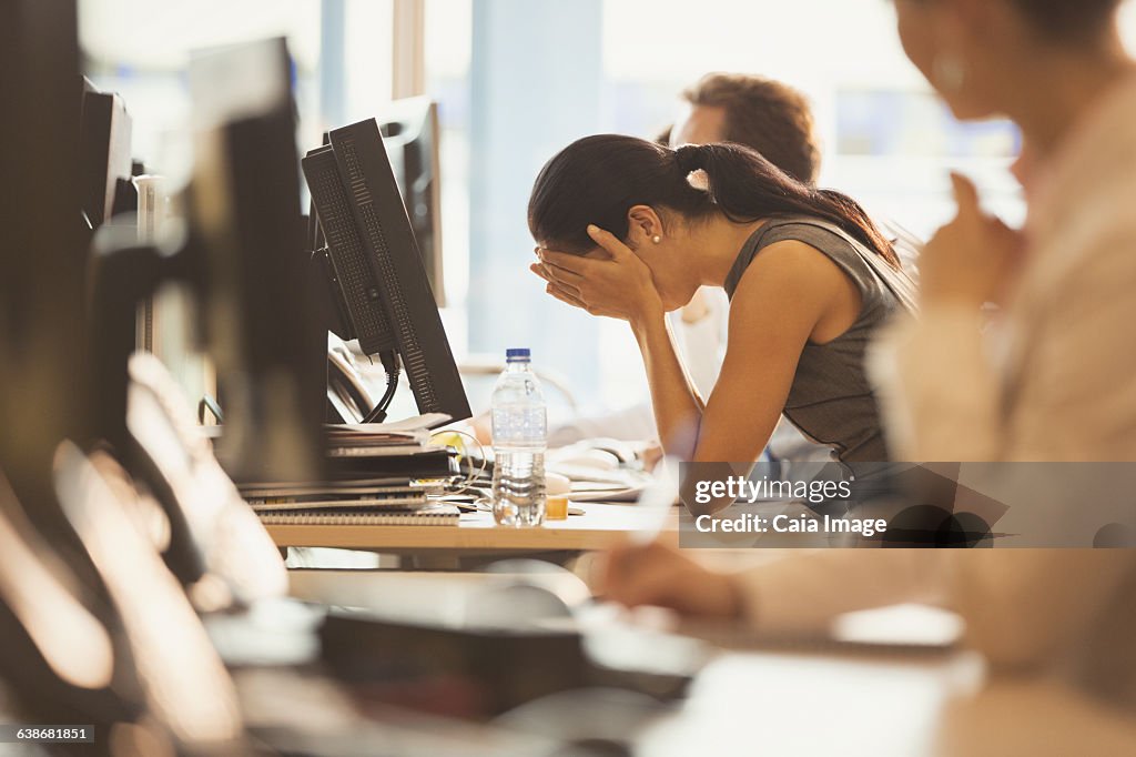 Stressed businesswoman with head in hands at office desk
