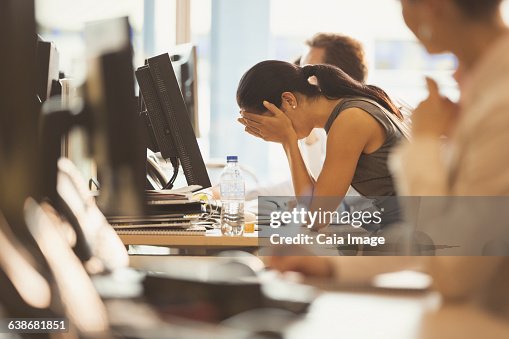 Stressed businesswoman with head in hands at office desk Stressed businesswoman with head in hands at office desk