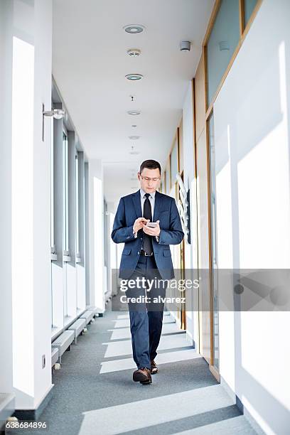 unternehmer mit smartphone im büro - person in suit construction stock-fotos und bilder