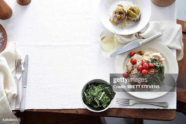 overhead view of meal table with plate of prosciutto wrapped figs, wilted spinach, cherry tomatoes, tuna steak and capers - prosciutto wrapped stock pictures, royalty-free photos & images