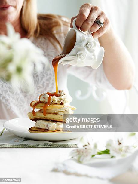 woman pouring toffee sauce from ornate jug on stack of pikelets - bolo tipo crepe imagens e fotografias de stock