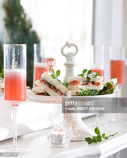 champagne flutes of pink champagne and crayfish sandwiches on cake stand - pink champagne stock pictures, royalty-free photos & images