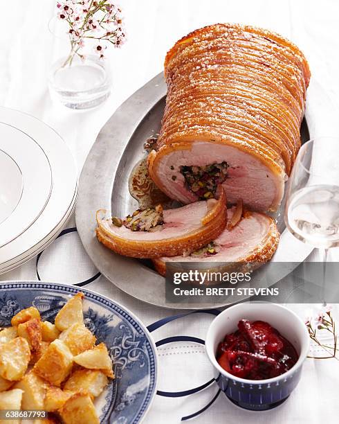 high angle view of stuffed roast pork joint with crispy crackling and roasted potatoes - crackling stock pictures, royalty-free photos & images